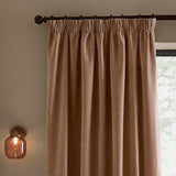 Heath Washed Velvet Pencil Pleat Curtains in Cotta, terracotta-pink fabric with pencil pleat heading on a dark pole, shown hanging beside a window in a living room setting.