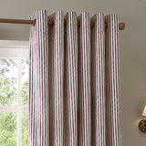 Hebden cotton fully lined eyelet curtains in beetroot red vertical stripe on cream, shown on a wooden pole against a neutral wall near a window.