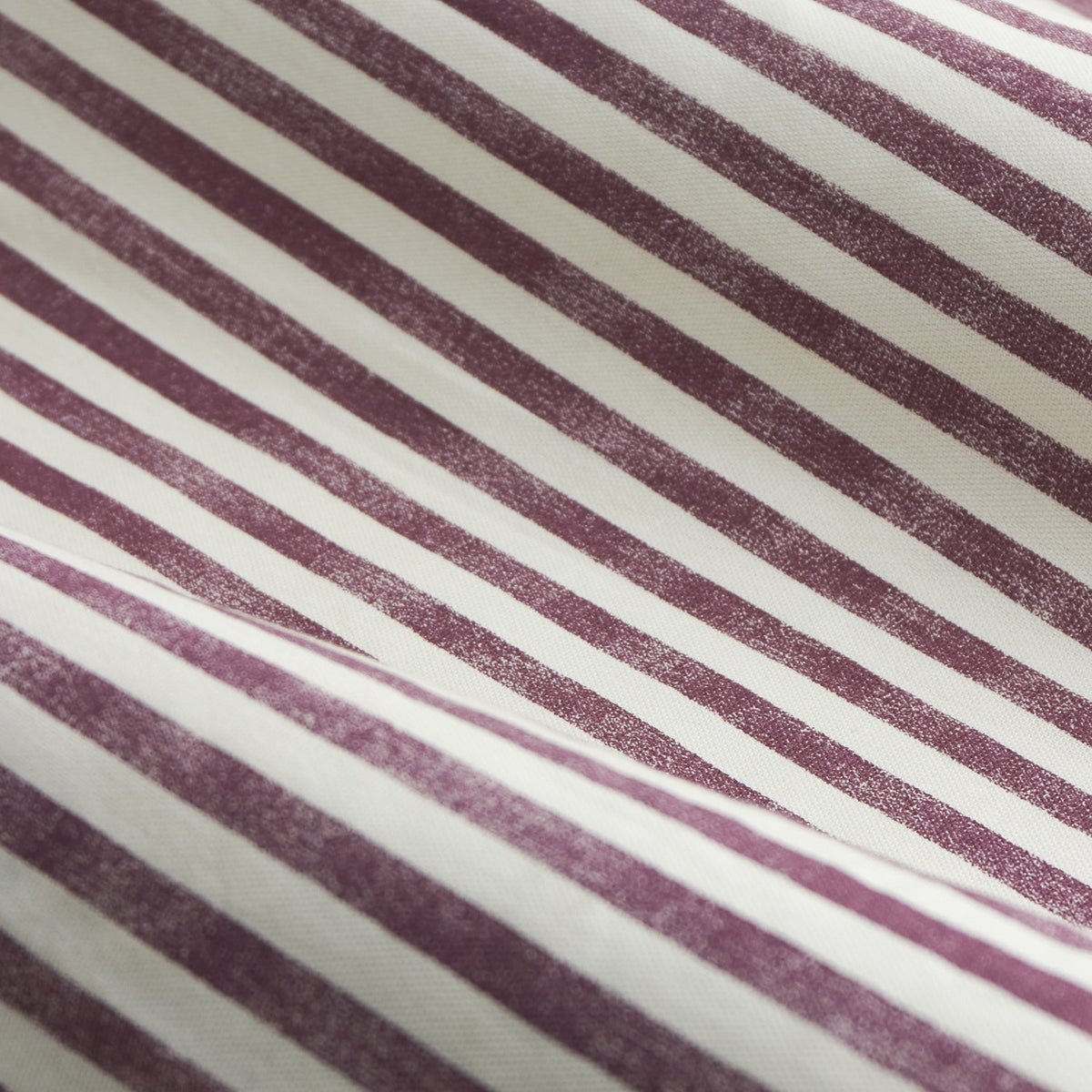 Close-up of Hebden Cotton Fully Lined Eyelet Curtains fabric in beetroot red, showing a diagonal striped print with a chalky, hand-printed texture against a cream ground.