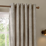 Hebden Cotton Fully Lined Eyelet Curtains in chocolate brown stripe on cream, hung on a wooden pole with eyelet heading beside a window in a neutral-toned room.