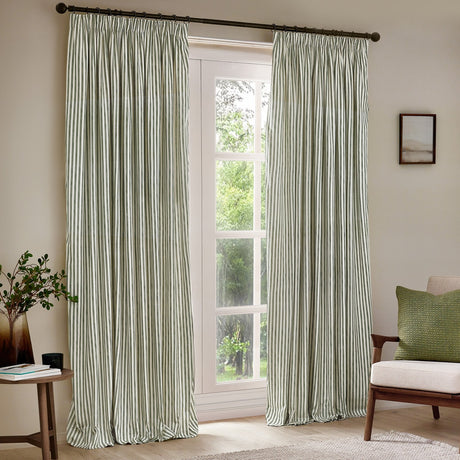 Hebden striped cotton pencil pleat curtains in forest green and off-white, shown as a pair on a dark pole in a living room window setting.