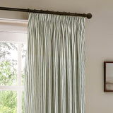 Hebden Striped Cotton Pencil Pleat Curtains in forest green, pinch-pleat heading on a dark rod, hung at a window in a neutral-toned room.