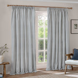 Hebden fully lined cotton pencil pleat curtains in mineral blue stripe, shown as a pair on a wooden pole in a living room window setting.