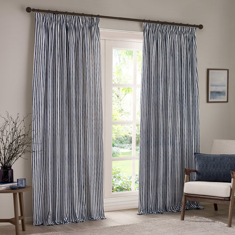 Hebden Striped Cotton Pencil Pleat Curtains in navy and white, shown pencil-pleated on a rail either side of a glazed door in a living room setting.