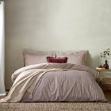 Hebden Cotton Melange Duvet Cover Set in Beetroot, showing beetroot-and-cream striped bedding with matching pillowcases and a beetroot cushion on a bed in a neutral bedroom setting.