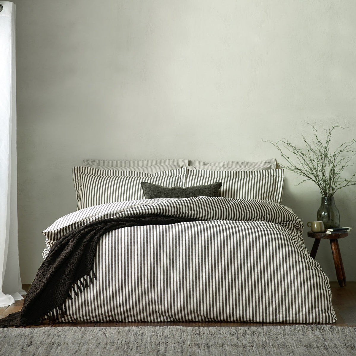 Hebden Cotton Melange Duvet Cover Set in Black on a bed with matching pillowcases, a dark textured throw, and a plain square cushion in a bedroom setting.