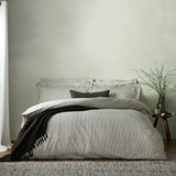 Hebden Cotton Melange Duvet Cover Set in Black on a bed with matching pillowcases, a dark textured throw, and a plain square cushion in a bedroom setting.