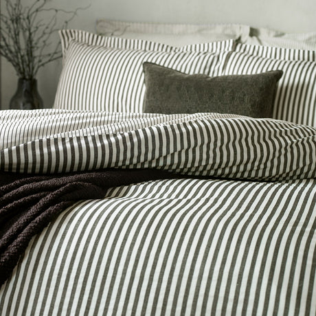 Hebden Cotton Melange Duvet Cover Set in Black, shown on a bed with matching pillowcases in fine black and cream stripes, styled with a chunky black throw and textured cushion.