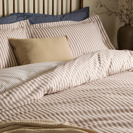 Hebden Cotton Melange Duvet Cover Set in Caramel, featuring cream and beige striped cotton bedding with matching pillowcases on a bed with a wooden headboard.