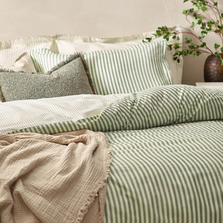 Hebden Cotton Striped Duvet Cover Set in Forest on a bed, showing reversible green and cream stripes with matching pillowcases, textured cushions and a beige throw.
