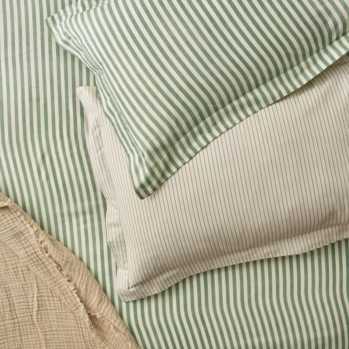 Hebden Cotton Striped Duvet Cover Set in Forest, reversible with wide green-and-cream stripes on one side, fine green pinstripes on the other, styled with matching pillowcases.