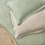 Hebden Cotton Striped Duvet Cover Set in Forest, reversible with wide green-and-cream stripes on one side, fine green pinstripes on the other, styled with matching pillowcases.