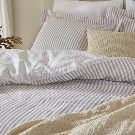 Hebden Cotton Melange Duvet Cover Set in mauve, styled on a bed with matching pillowcases in a fine mauve-and-white stripe, layered with textured cream cushions and throw.