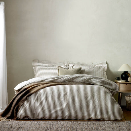 Hebden Cotton Melange Duvet Cover Set in Mole, striped brown and white cotton bedding on a bed with matching pillowcases and a brown throw, in a neutral bedroom.