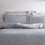 Hebden Cotton Striped Duvet Cover Set in navy and off-white, shown with matching pillowcases and a fine mélange stripe pattern on a bed against a plain light background.