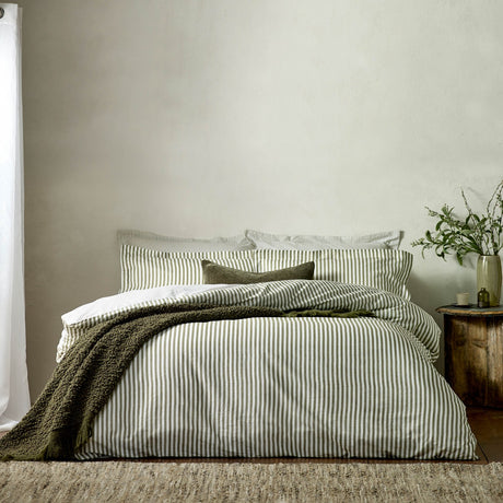 Hebden Cotton Melange Duvet Cover Set in olive green stripe on white, styled on a bed with matching pillowcases and a green textured throw against a neutral bedroom wall.
