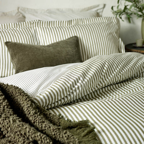 Hebden Cotton Melange Duvet Cover Set in olive green stripe on white, shown on a bed with matching pillowcases, a textured olive cushion, and a bouclé throw.