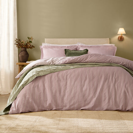 Hebden Cotton Melange Duvet Cover Set in Rosewood pink and cream stripe on a bed with matching pillowcases, styled with a sage green throw in a bedroom setting.