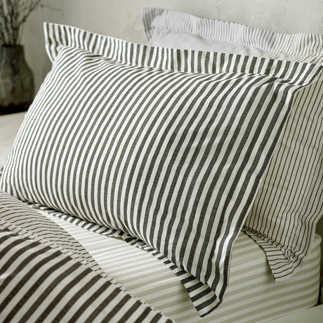 Hebden Striped Cotton Pillowcase Pair in Black, shown on a bed with matching striped pillowcases and bedding in a bedroom setting.