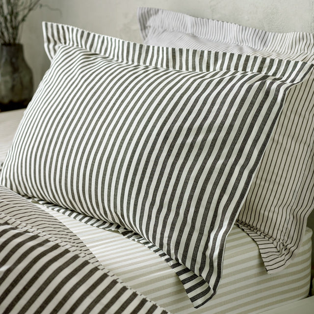 Hebden Striped Cotton Pillowcase Pair in Black, shown on a bed with matching striped pillowcases and bedding in a bedroom setting.