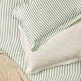 Hebden Melange Cotton Pillowcase Pair in Forest, showing layered green and cream striped cotton pillowcases and matching duvet cover on a bed.