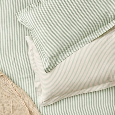 Hebden Melange Cotton Pillowcase Pair in Forest, showing layered green and cream striped cotton pillowcases and matching duvet cover on a bed.