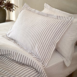 Hebden Melange Cotton Pillowcase Pair in mauve-grey stripe on cream, shown styled on a bed with matching striped duvet and sheets.