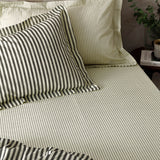 Hebden Striped Cotton Fitted Sheet in black on a bedroom bed, cream cotton fabric with fine charcoal vertical stripes, styled with matching striped pillowcases.