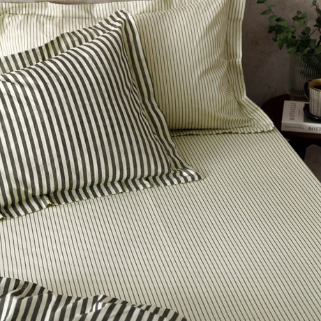 Hebden Striped Cotton Fitted Sheet in black on a bedroom bed, cream cotton fabric with fine charcoal vertical stripes, styled with matching striped pillowcases.