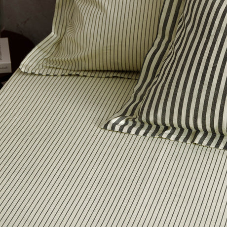 Hebden Striped Cotton Fitted Sheet in Black on bed, showing cream ground with fine charcoal pinstripes across sheet and matching pillowcases.
