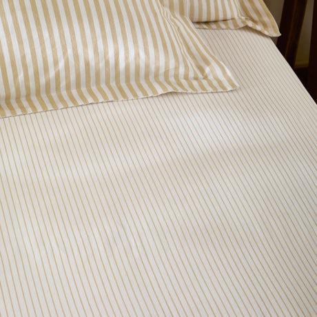 Hebden Striped Cotton Fitted Sheet in honey yellow, showing cream cotton fabric with narrow sandy gold stripes on a fitted bed with matching pillowcases.