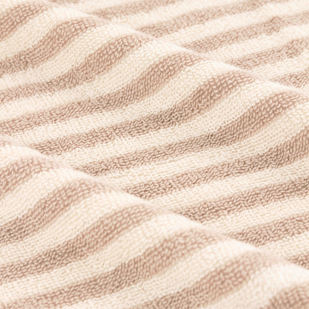 Close-up of the Hebden Striped Cotton Towel in natural, showing vertical beige and cream stripes on soft cotton terry fabric.