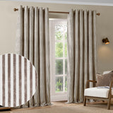 Hebden Cotton Printed Eyelet Curtains in Chocolate, striped brown and cream cotton panels with eyelet header, shown framing a window in a living room with an armchair.