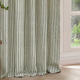 Hebden Cotton Printed Eyelet Curtains in Forest, showing slim vertical green stripes on off-white cotton fabric, hung beside a window in a living space.