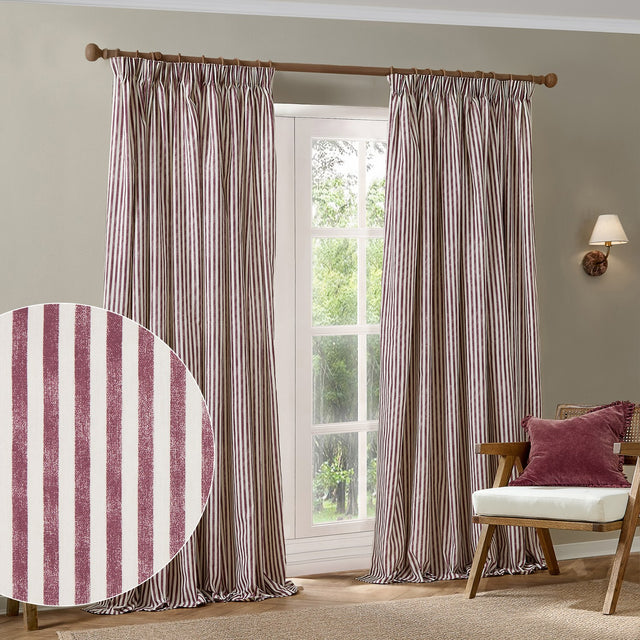 Hebden Striped Cotton Pencil Pleat Curtains in beetroot red and cream, pencil pleat header on a wooden pole, shown in a living room with an armchair and cushion.