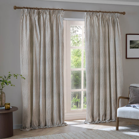 Hebden Striped Cotton Pencil Pleat Curtains in Mole hang from a wooden pole, showing fine mole-brown ticking stripes on pale cotton with a pencil pleat header.
