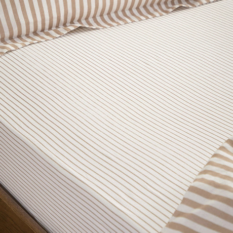 Hebden fitted sheet in caramel, pure cotton with fine striped pattern on a white ground, shown fitted to a mattress with a coordinating striped edge.