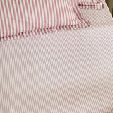 Hebden fitted sheet in rosewood, 100% cotton with fine rose-and-cream stripes, corner elastic visible beneath a matching pillowcase.
