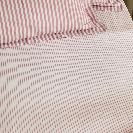 Hebden fitted sheet in rosewood, 100% cotton with fine rose-and-cream stripes, corner elastic visible beneath a matching pillowcase.