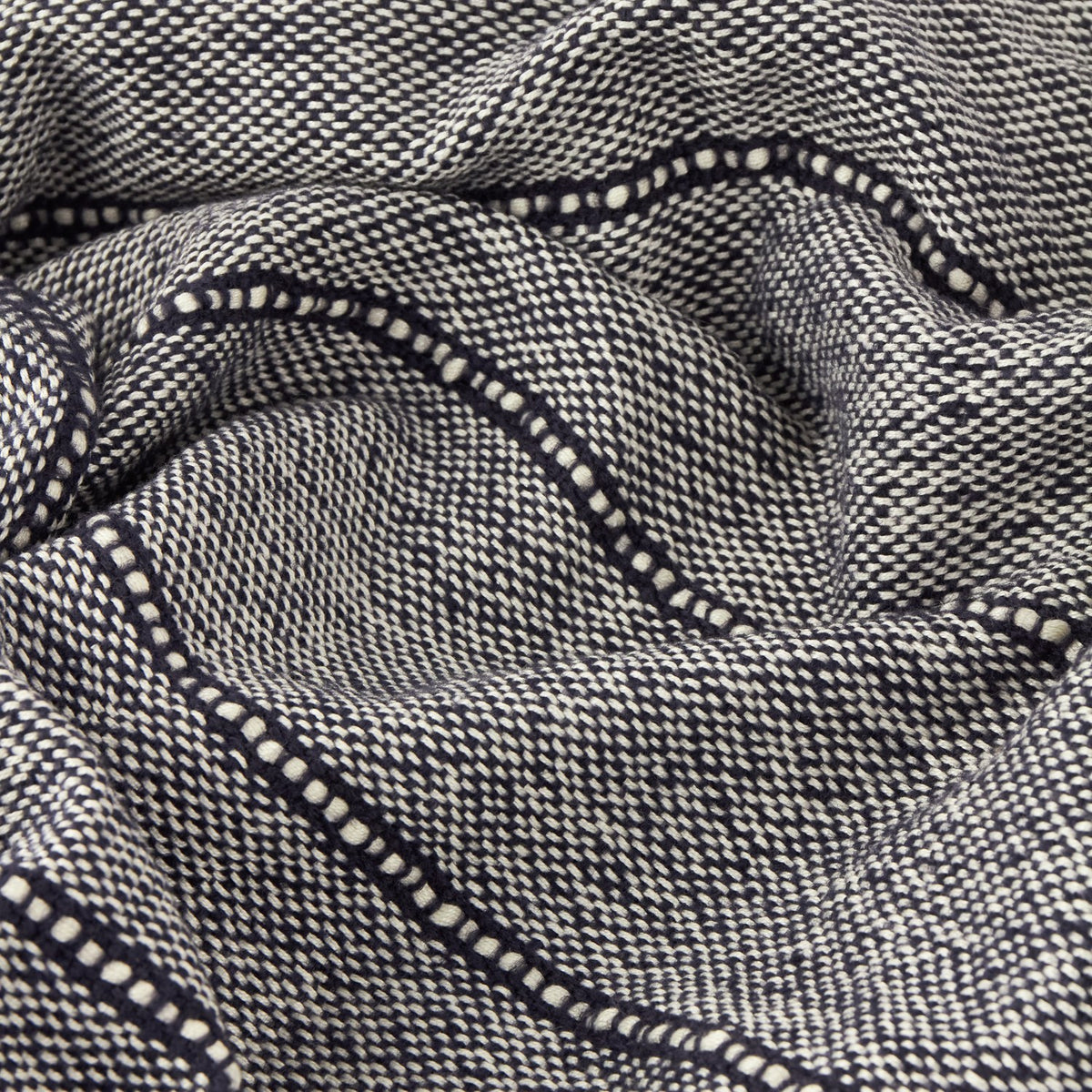 Close-up of the Hedon Striped Polyester Throw in navy, showing a woven navy and cream marl texture with a subtle linear stripe detail, draped in soft folds.