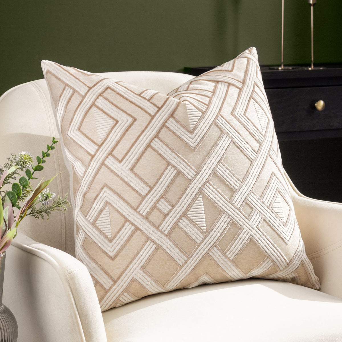 Henley Jacquard Velvet Cushion in warm taupe with raised off-white geometric lattice pattern, styled on a cream armchair in a living room setting.