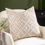 Henley Jacquard Velvet Cushion in warm taupe with raised off-white geometric lattice pattern, styled on a cream armchair in a living room setting.