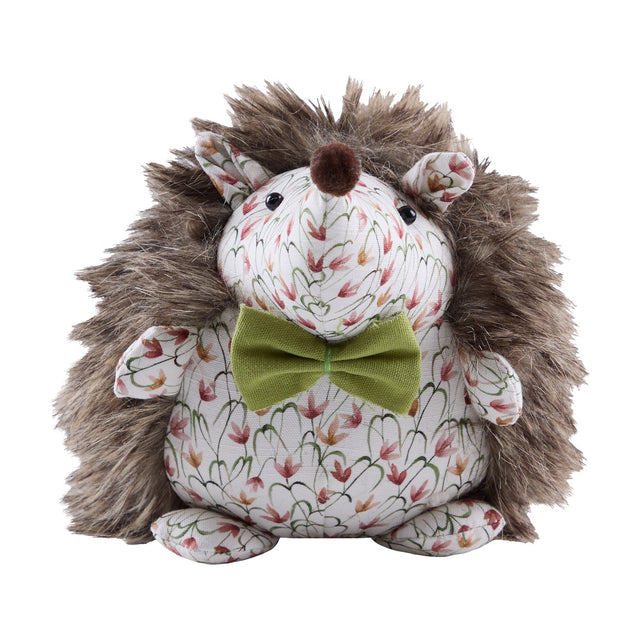 Henrietta Polyester Door Stop shaped like a hedgehog with shaggy brown faux fur back, cream floral fabric face and belly, a pom-pom nose, and an olive-green bow, on a plain white background.