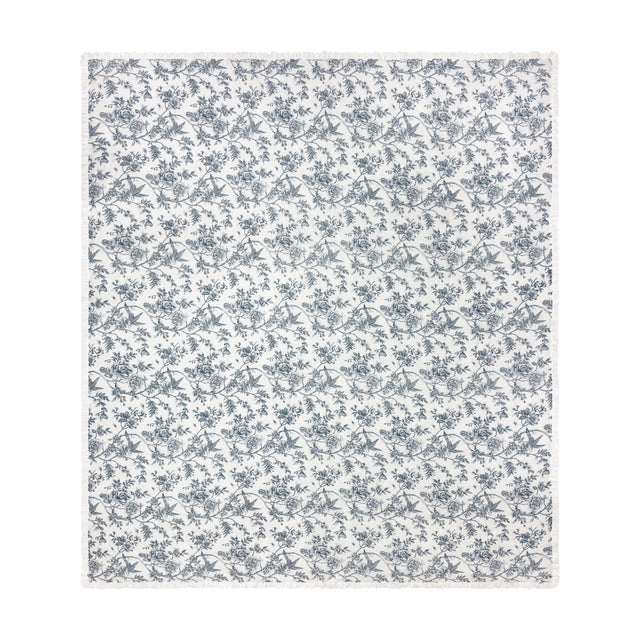 Hermione linen cotton bedspread in ivory blue, quilted diamond-pattern fabric with a fine-line Toile de Jouy floral and bird print, finished with a ruffled edge, shown on a white background.