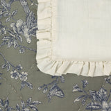 Hermione Linen Cotton Bedspread in Moss, corner detail showing cream ruffled frill edging and moss-green cotton with blue and cream Toile de Jouy floral, bird and butterfly print.