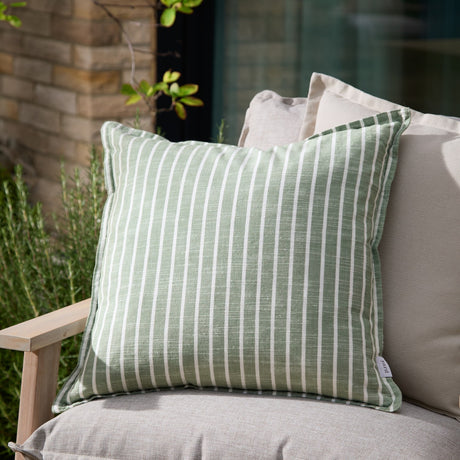 Hessle Stripe Yarn-Dyed Cotton Cushion in eucalyptus green with white pinstripes, shown on an outdoor sofa alongside neutral cushions in a garden setting.