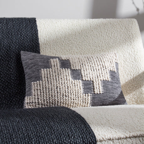 Himal Abstract Cotton Cushion in Dusk, an oblong lumbar cushion with a stepped grey and cream pattern combining flat weave and raised loop textures, shown on a boucle sofa.
