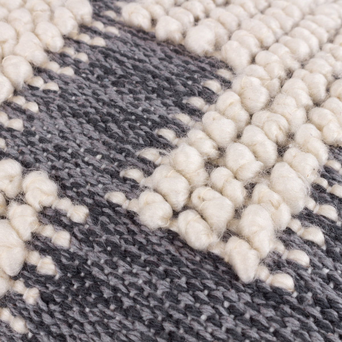 Close-up of the Himal Abstract Cotton Cushion in Dusk, showing raised cream knotted loops against flat woven charcoal grey cotton in a stepped, interlocking pattern.