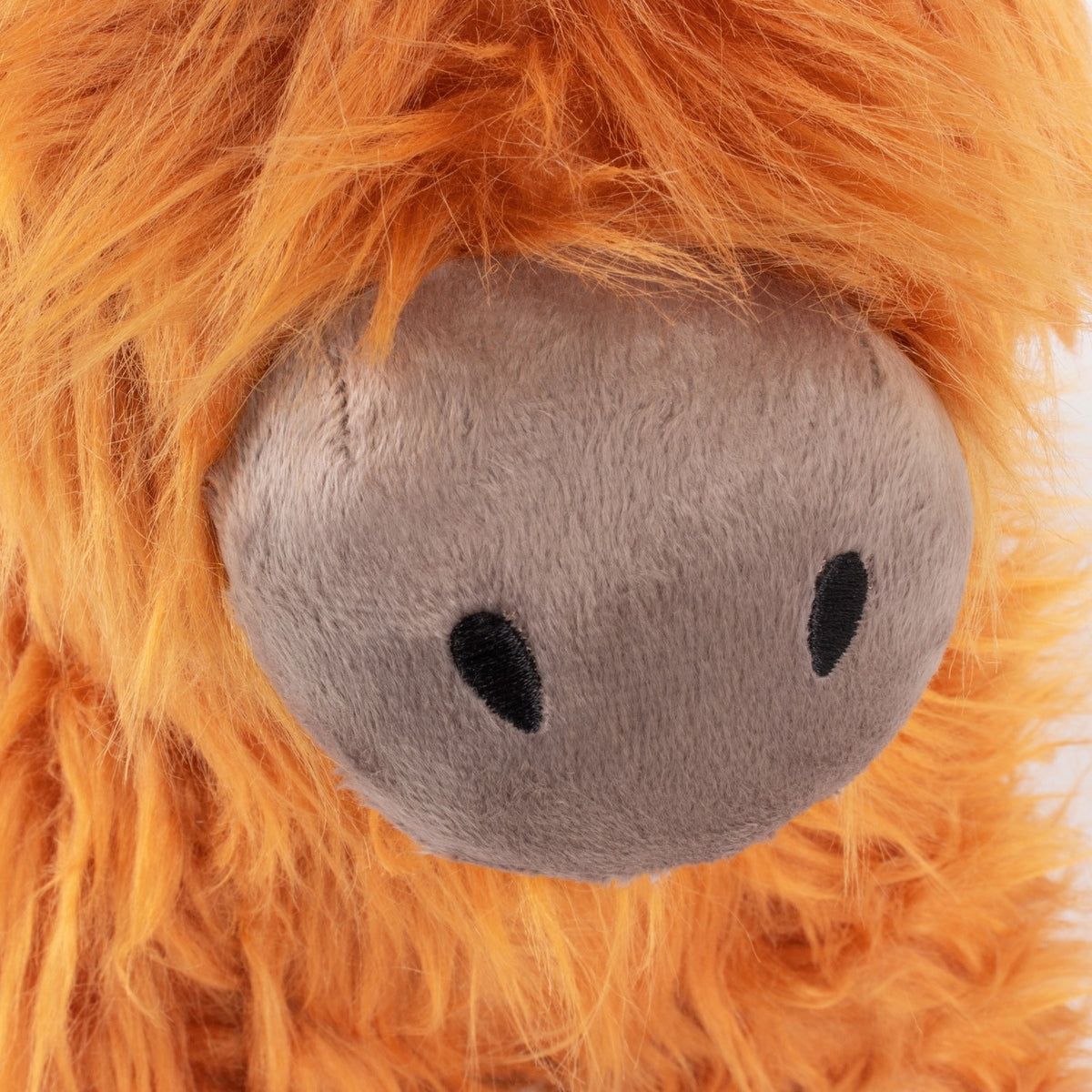 Close-up of the Highland Cow Velvet Faux Fur Door Stop in orange, showing shaggy fur fringe framing a grey velvet snout with embroidered black nostrils.