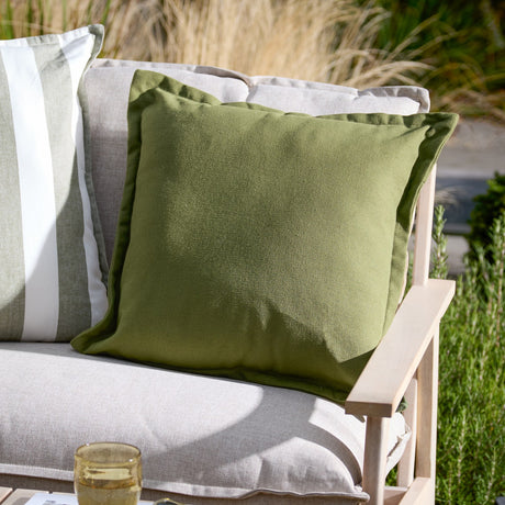 Holmfirth Canvas Plain Cotton Cushion in Eucalyptus green, a square 100% cotton canvas cushion with matt finish, shown on an outdoor sofa alongside a striped cushion.